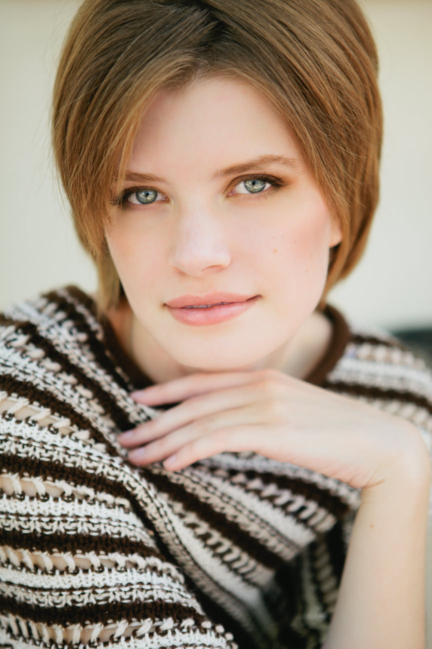 A woman wearing a brown striped top smiles for her headshots in Missoula Montana