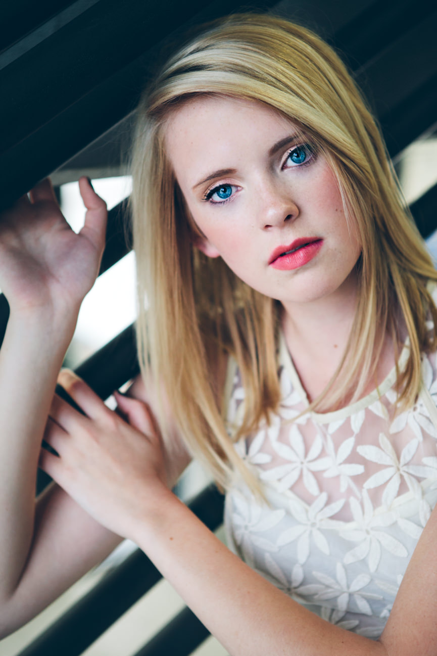 A young woman wearing a white floral top poses for headshots in Missoula Montana