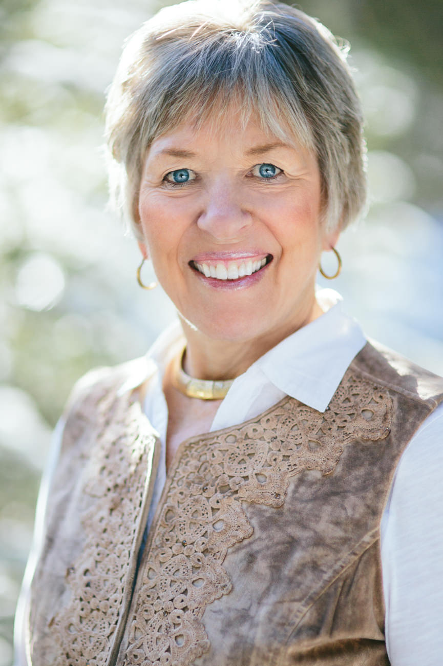 A woman wearing a brown vest smiles for her headshots in Missoula Montana