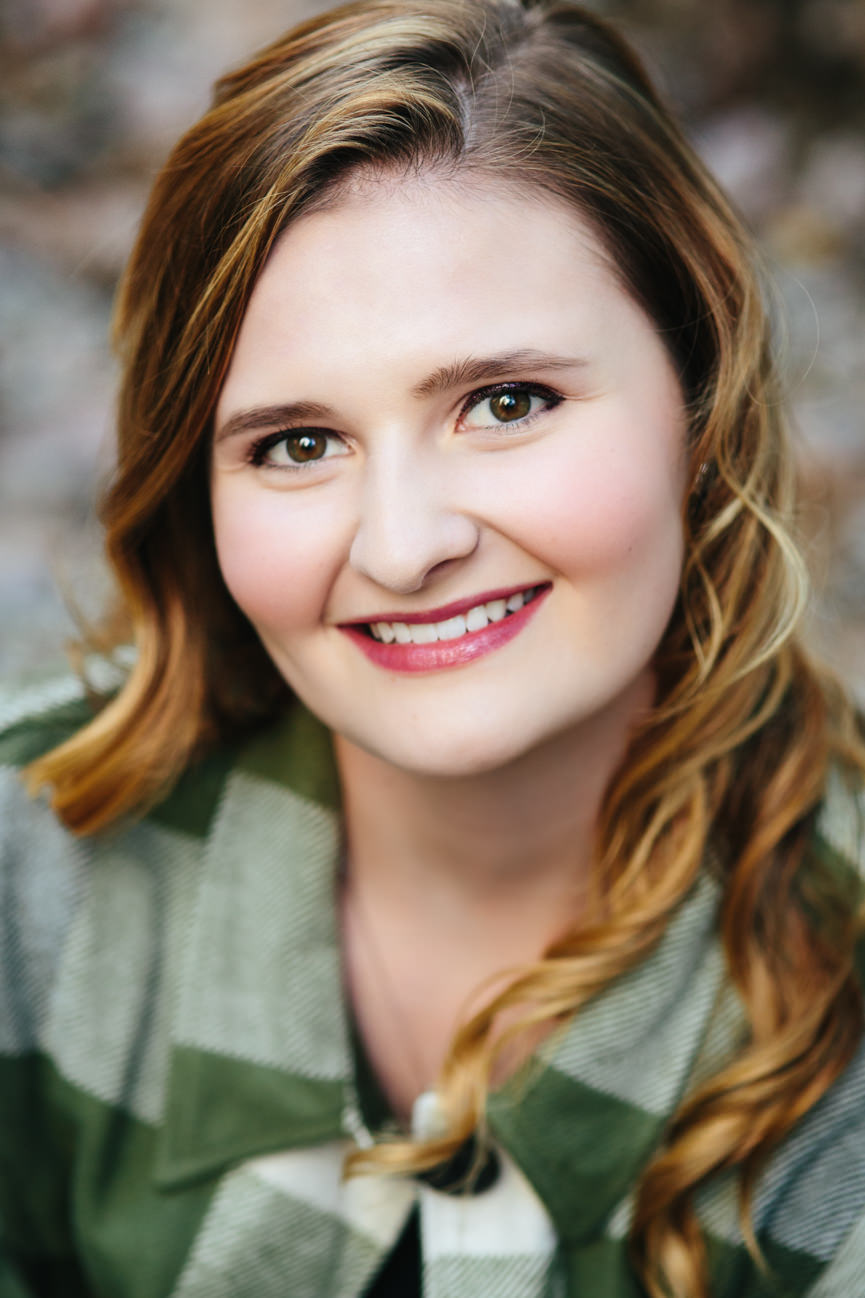 A young woman wearing green plaid smiles for her headshots in Missoula Montana