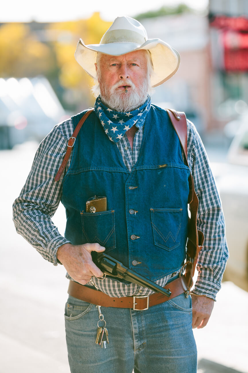 Nevada Pete holds a pistol and walks down the street in Cody Wyoming