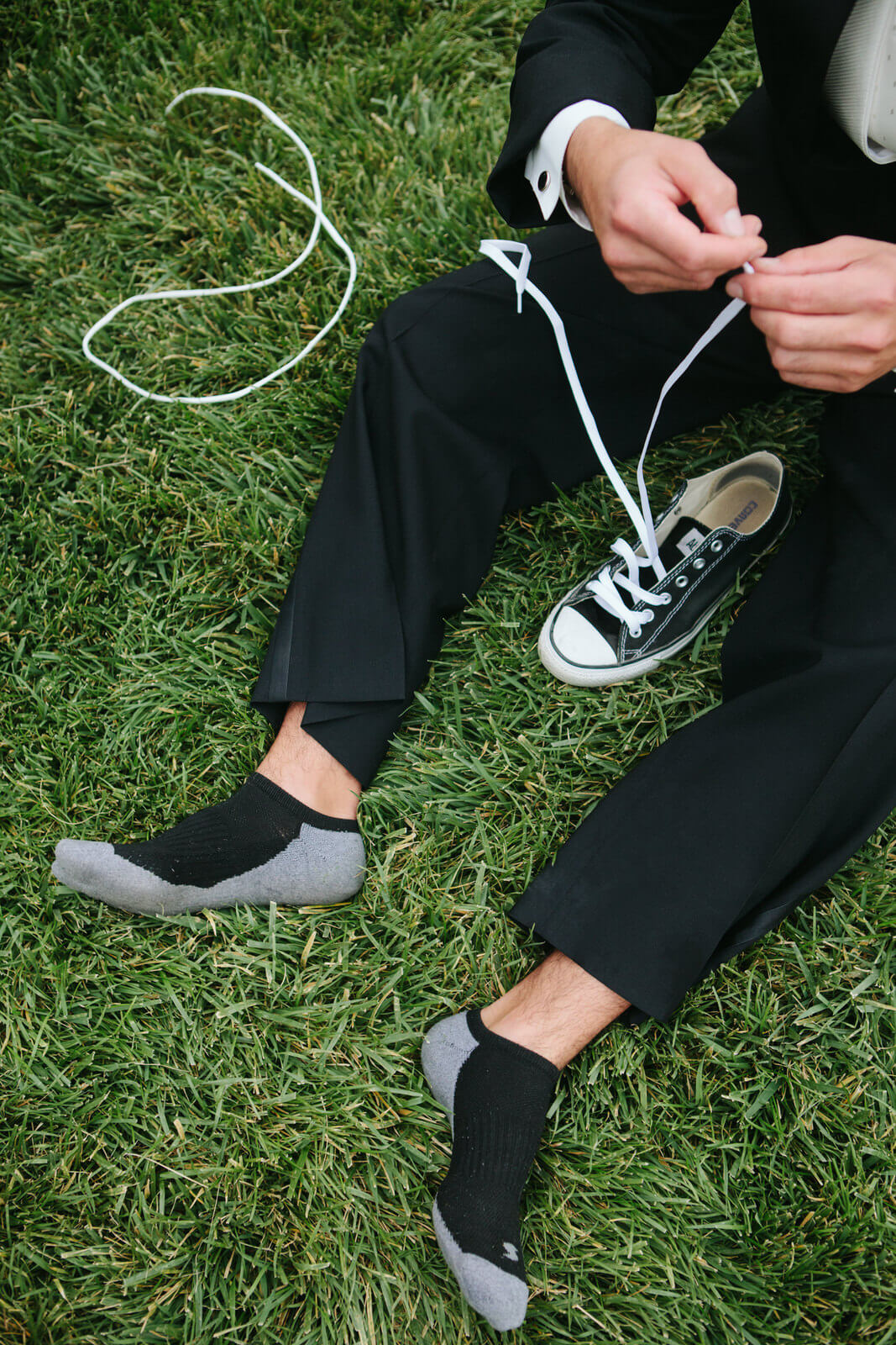 A groom laces his converse sneakers on his wedding day at the Slack Barn at the Teller Wildlife Refuge in Corvallis Montana on his wedding day