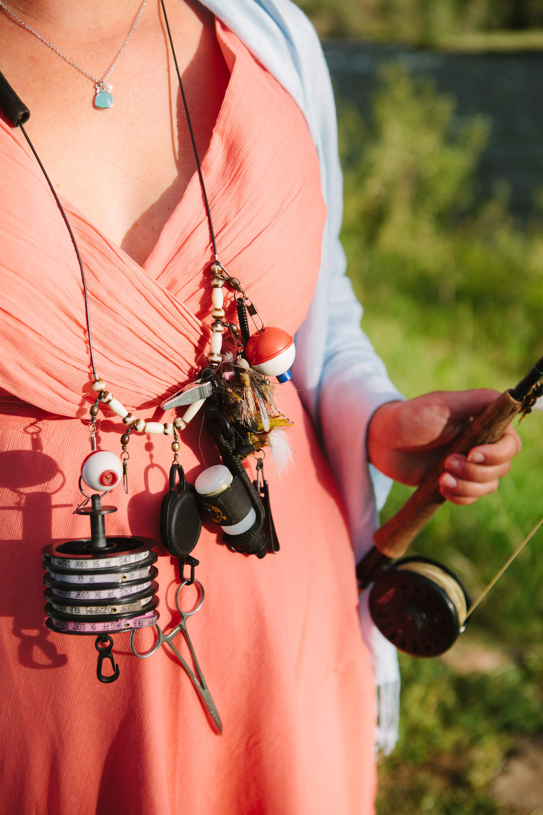A woman wears fly fishing gear around her neck and holds a fly rod in Absaroka Montana