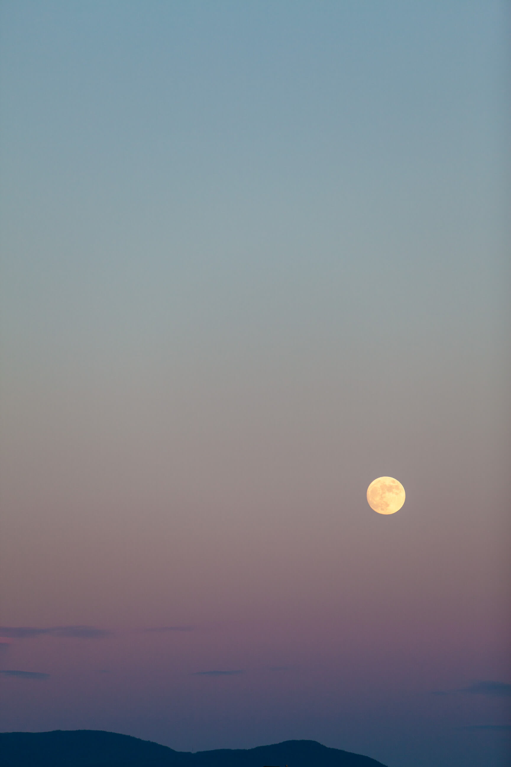 A full moon glows over mountains in Ovando Montana