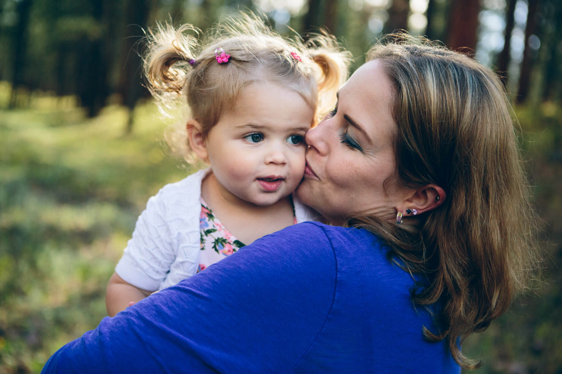 A mother kisses her toddler daughter during their family portraits in Potomac Montana