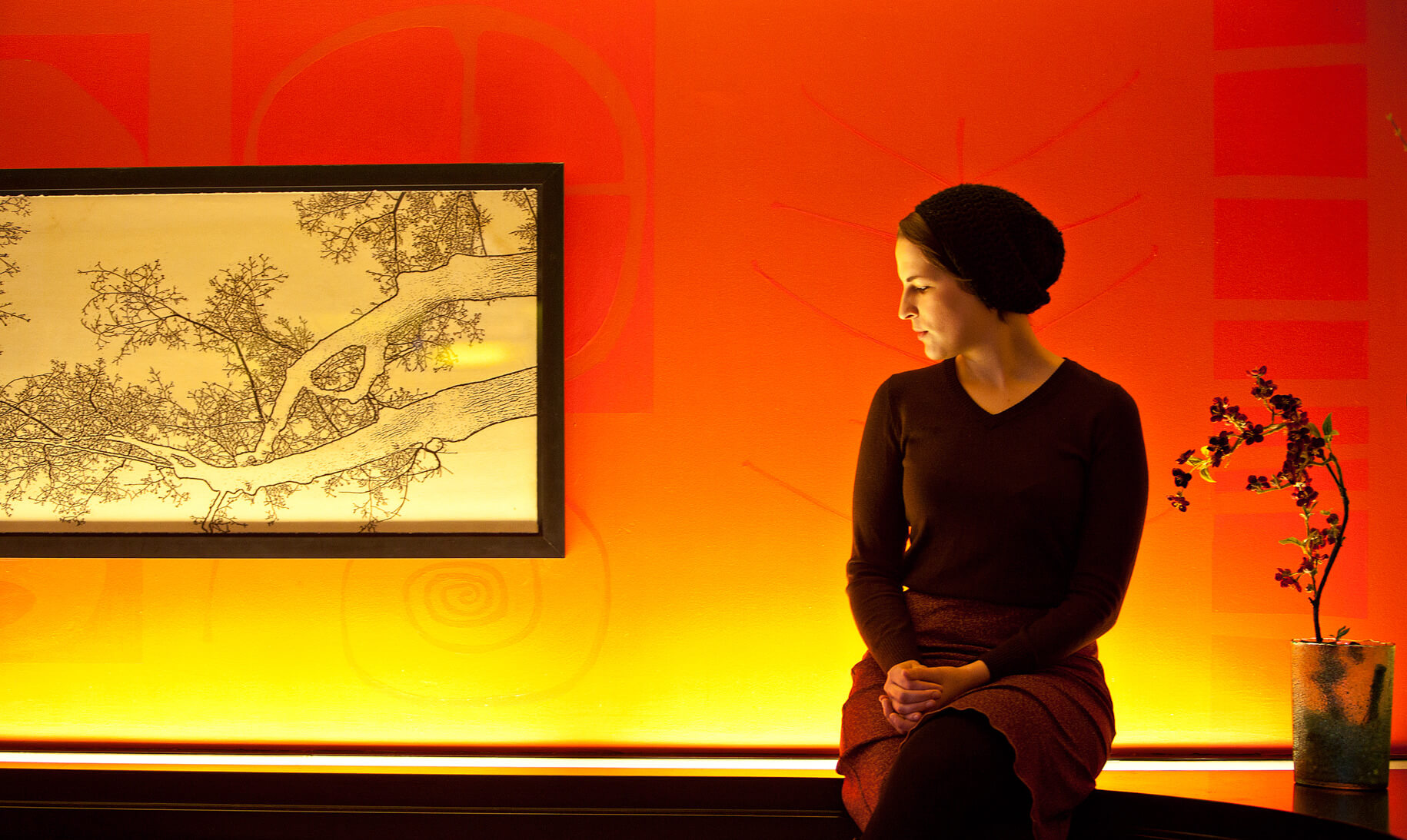 A woman sits against an orange wall in Missoula Montana