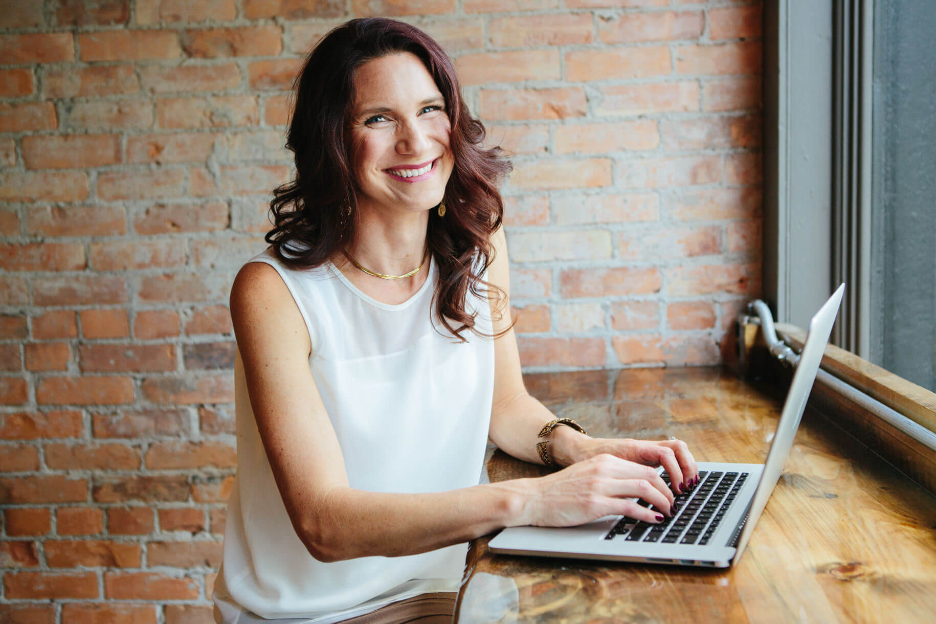 A woman smiles while using her laptop during her portrait session in Missoula Montana