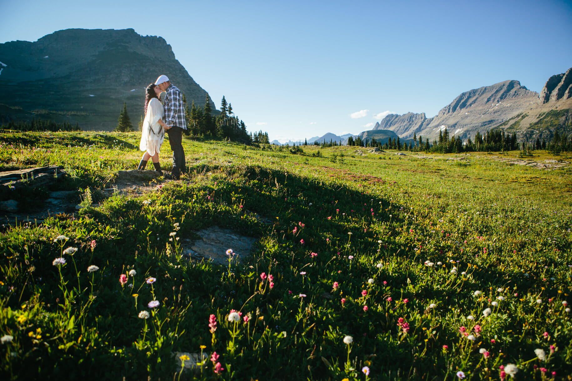 A bride and groom kiss amongst a field of wildflowers at their Glacier National Park elopement in Montana