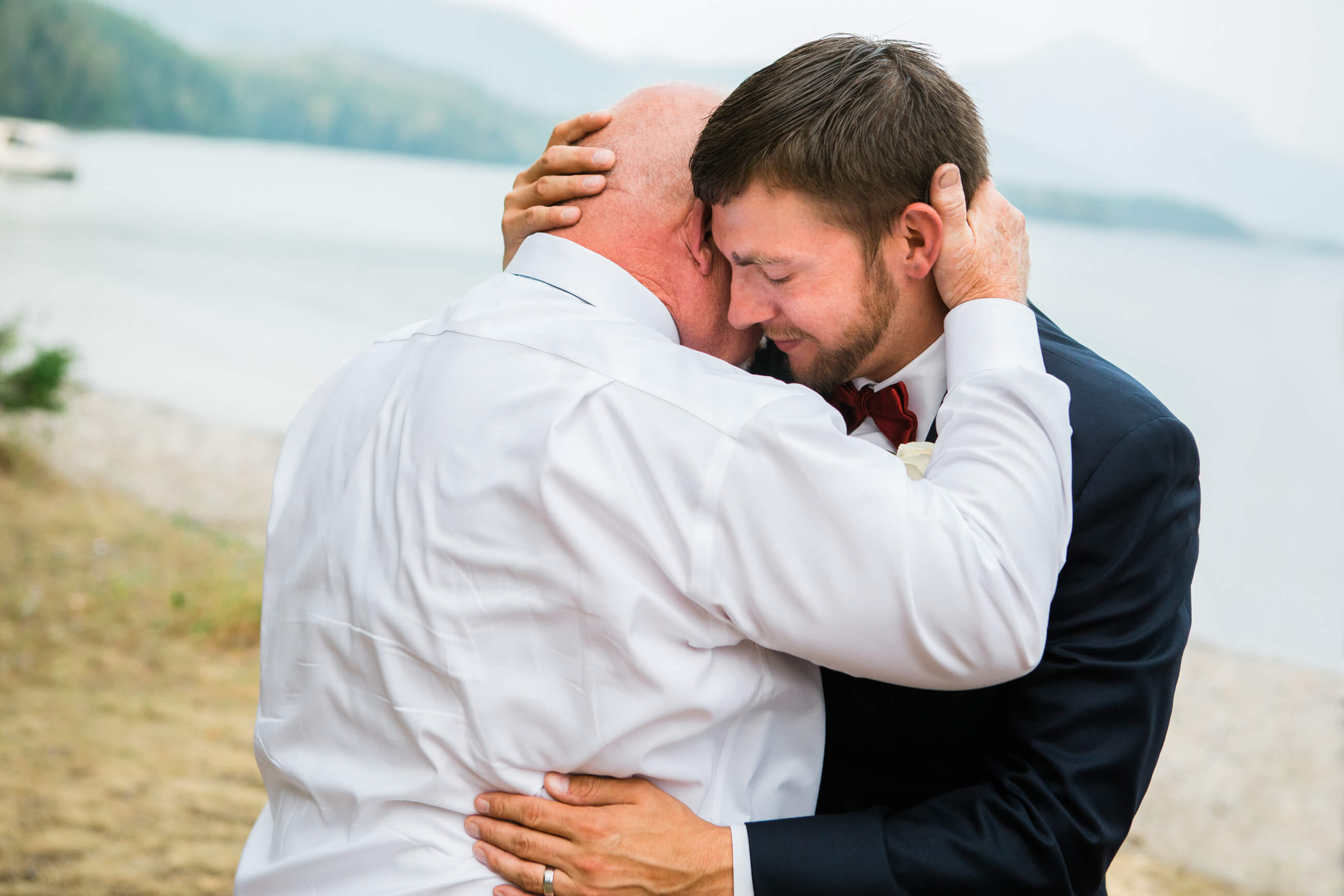 A groom and his father embrace during his Glacier National Park elopement in Montana