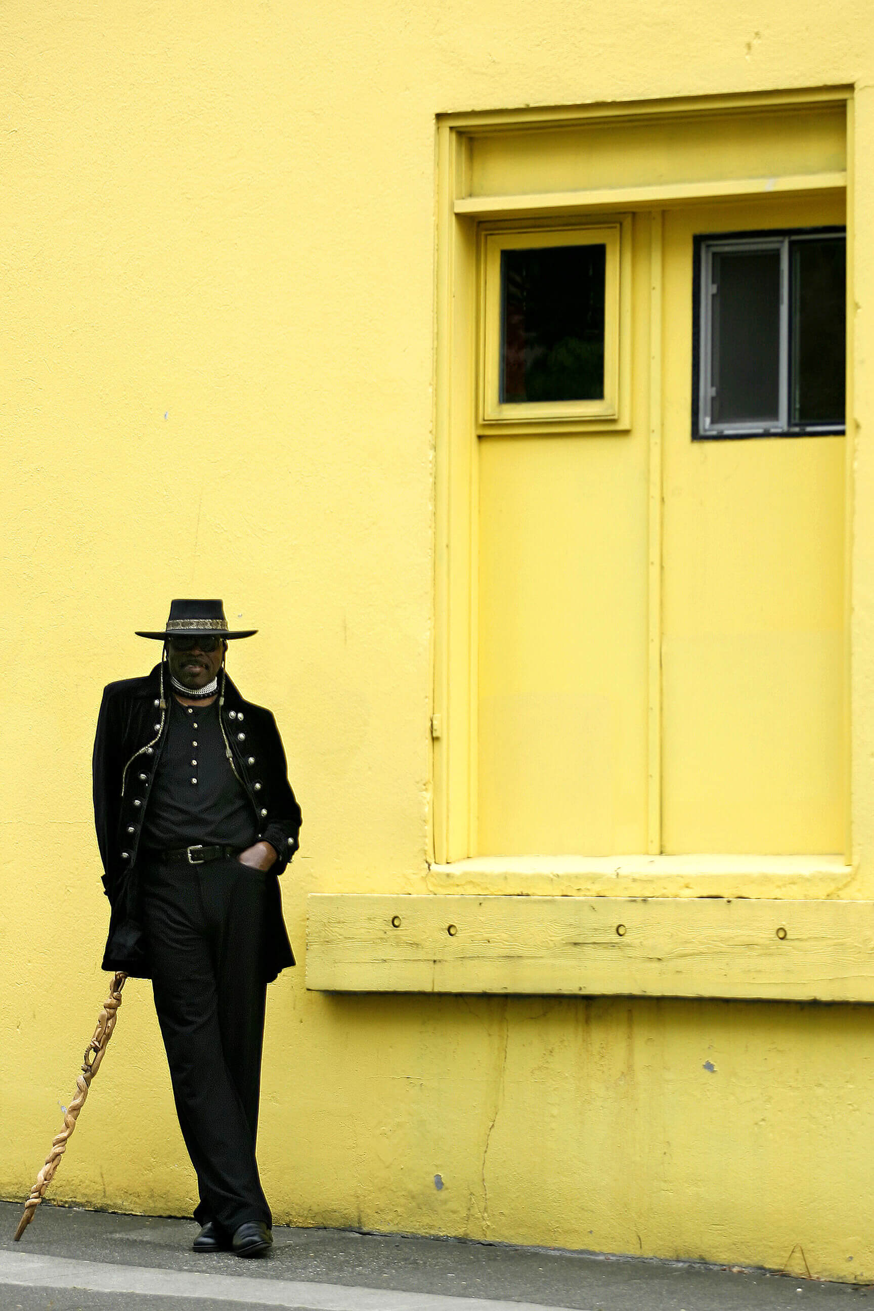 Vester Marshall leans on a carved cane near a bright yellow building in Seattle Washington