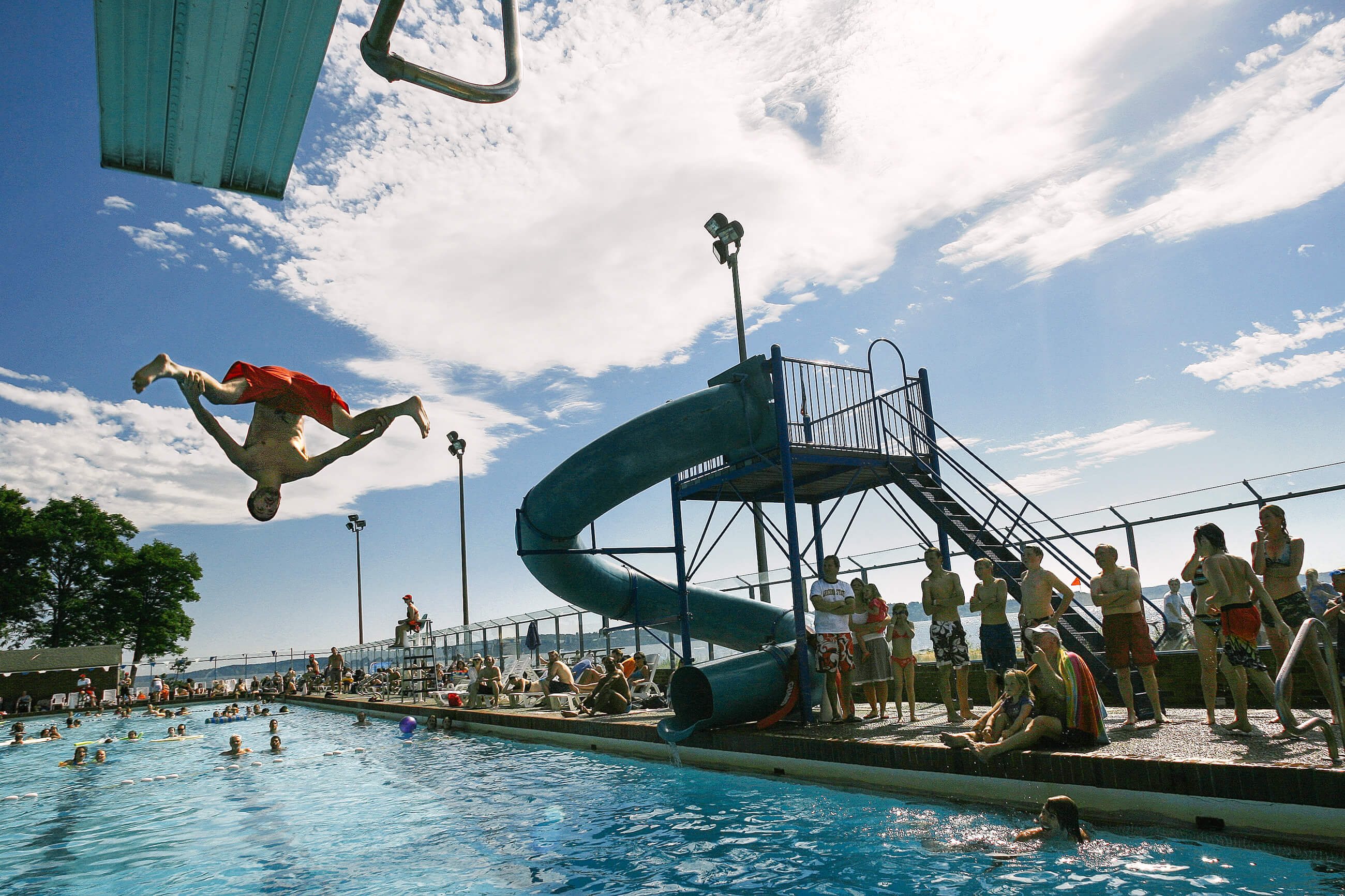 A young man dives off a diving board at Colman Pool in Seattle Washington