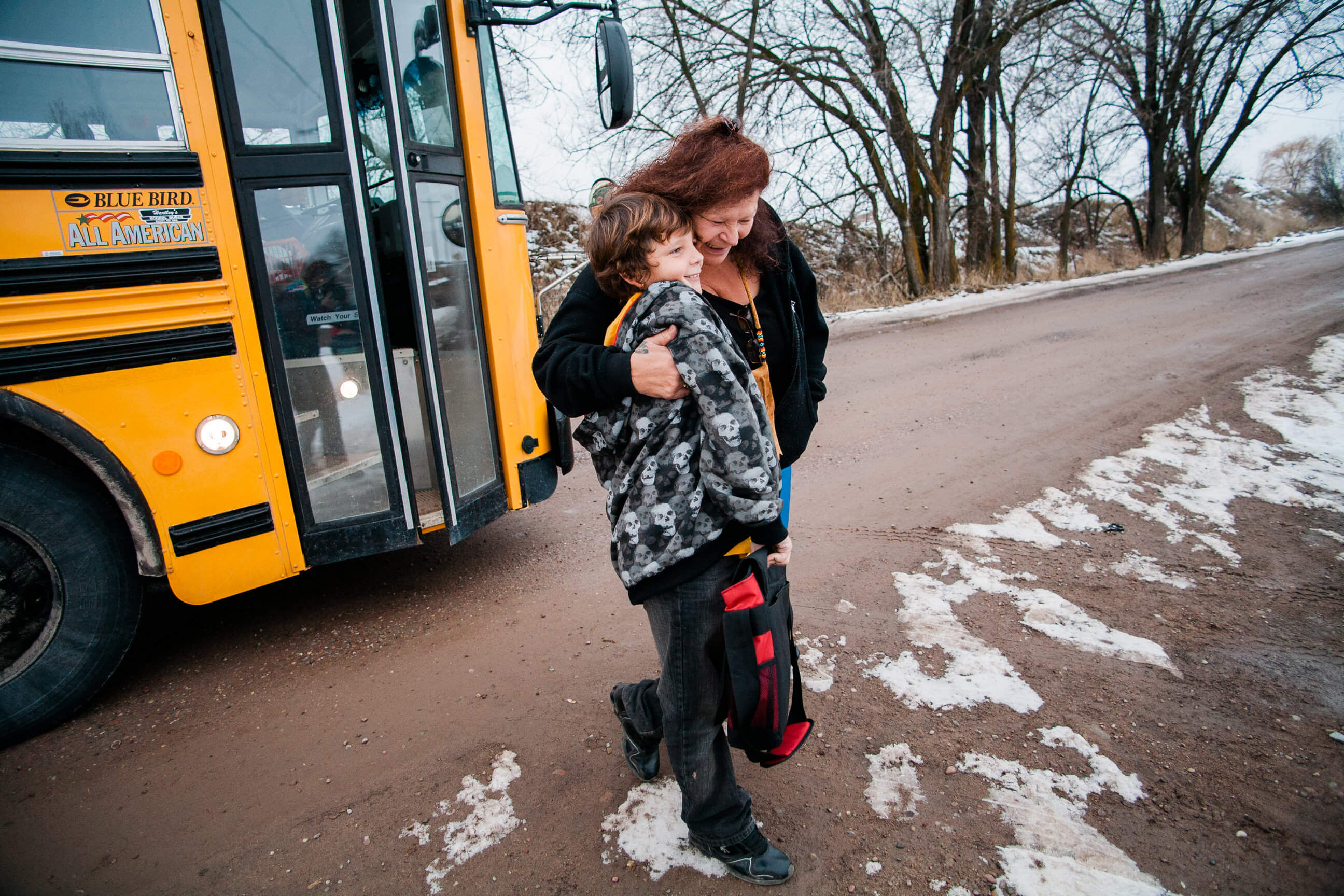 A grandmother greets her grandson as he gets off the bus in Pablo Montana