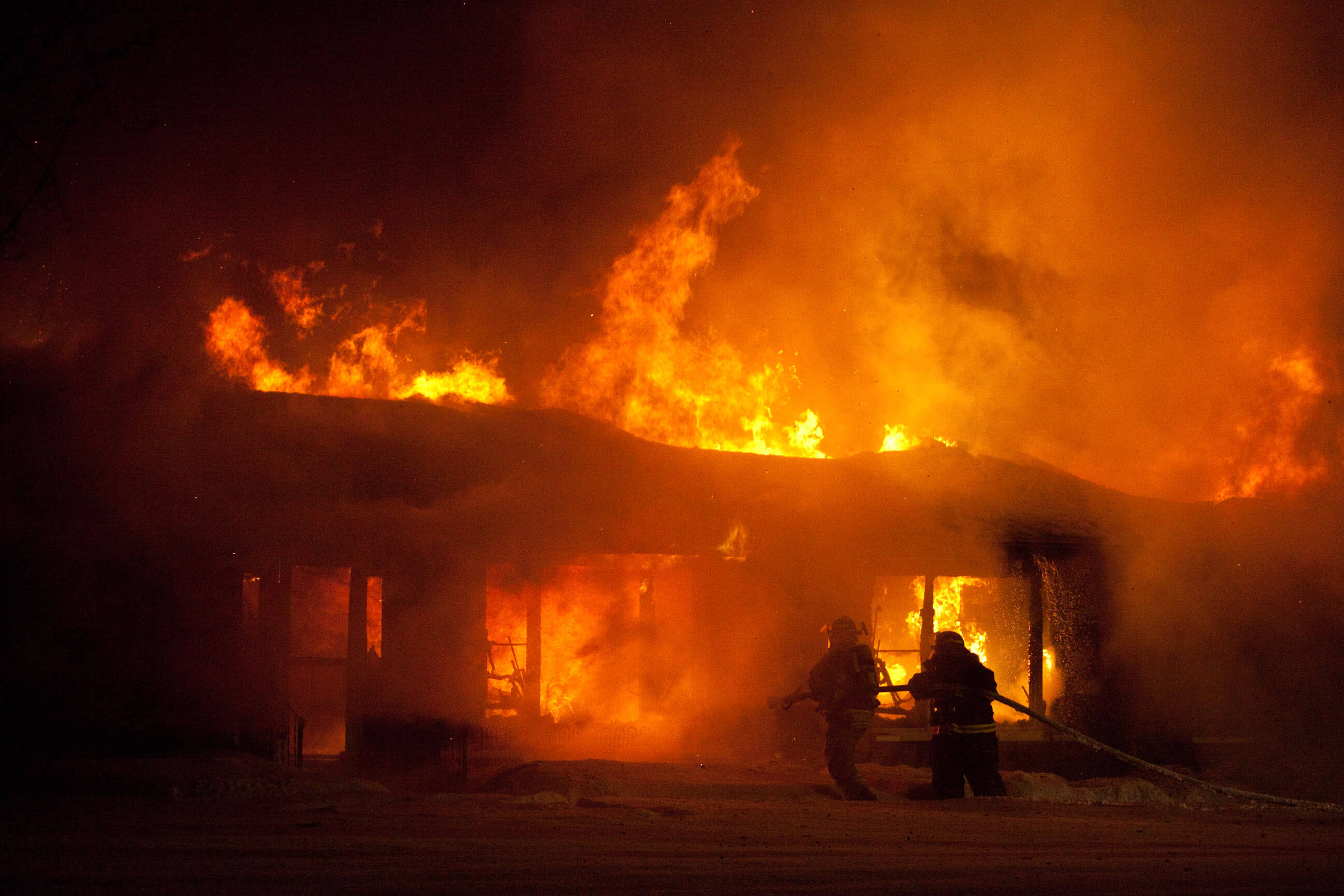 Firefighters drag a hose to tackle a giant house fire in Ladysmith Wisconsin