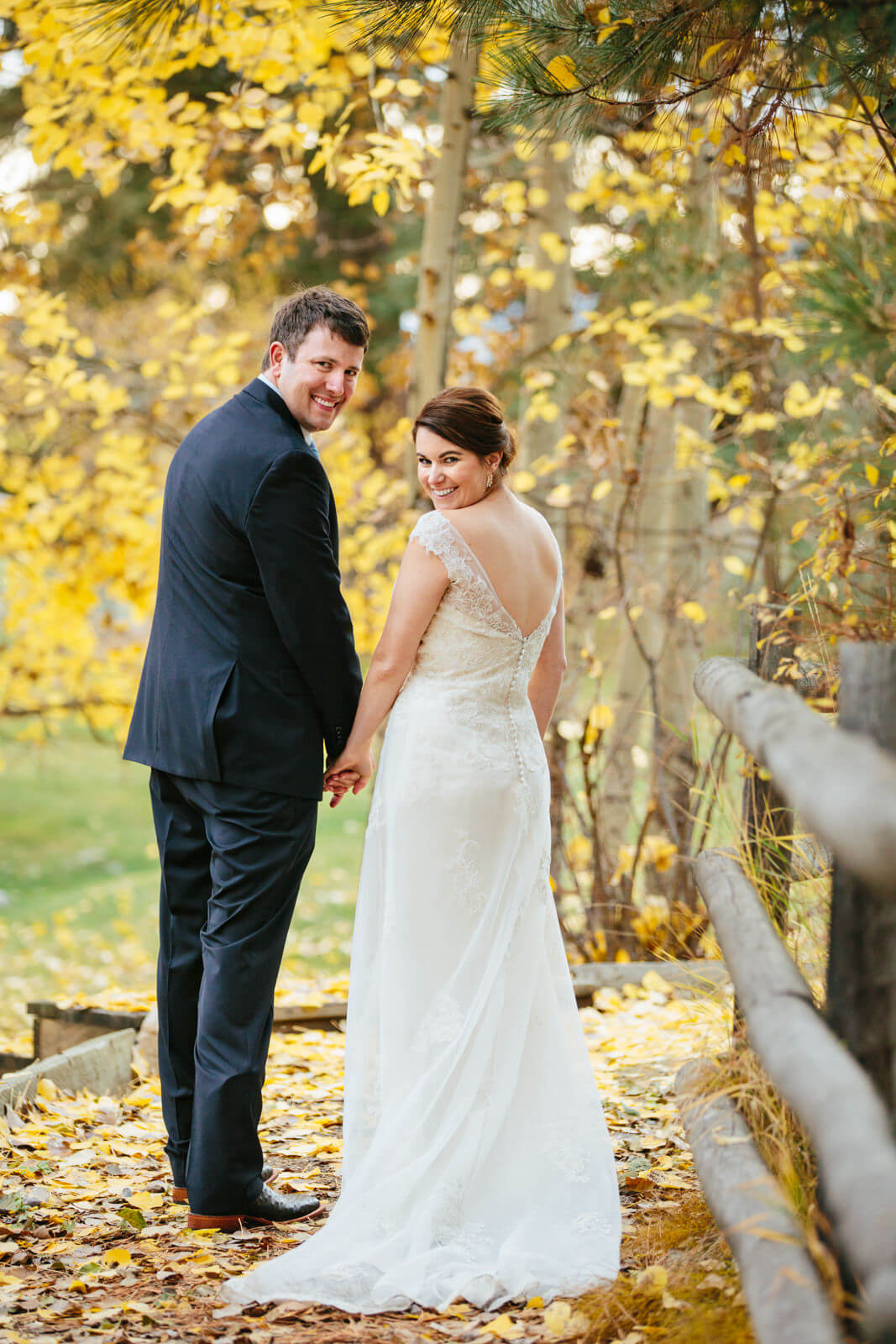 A bride and groom smile against a backdrop of autumn leaves at their Triple Creek Ranch elopement in Darby Montana