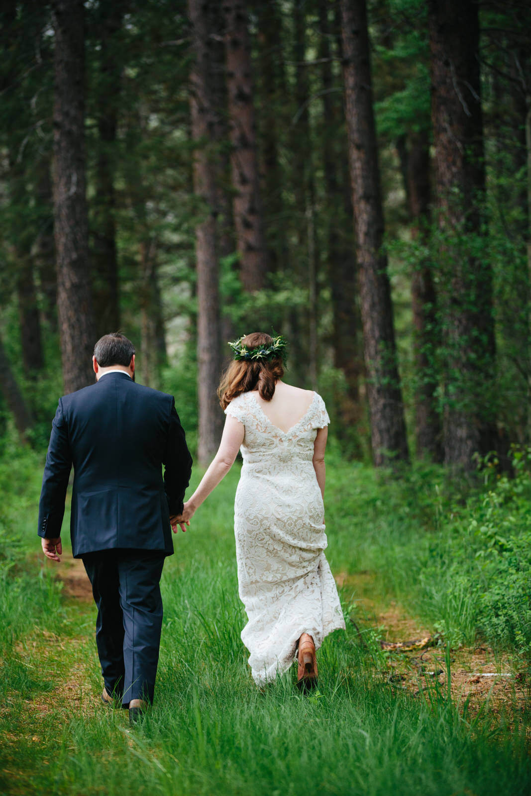 A couple walks through a forest at their Triple Creek Ranch wedding in Darby Montana
