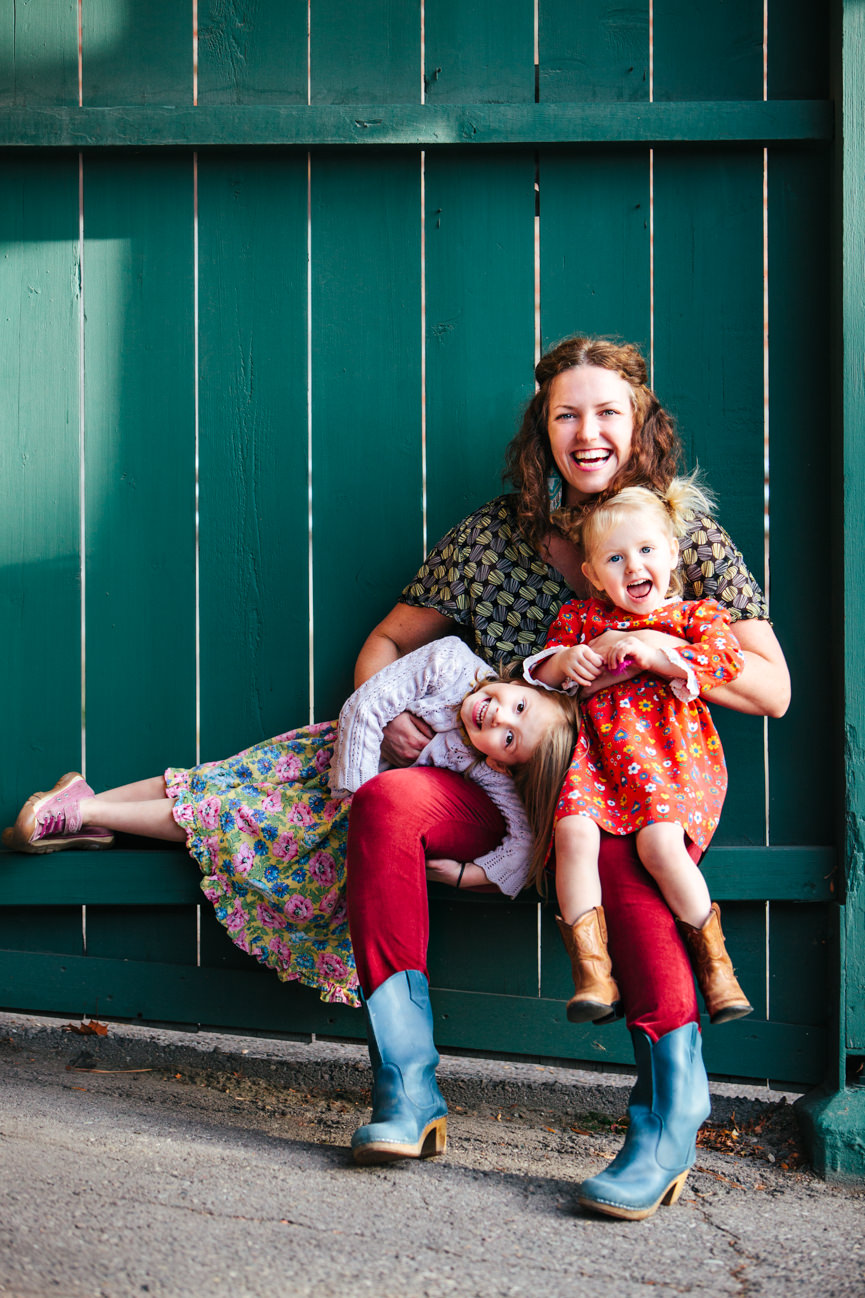 A woman business owner embraces her two daughters as they laugh and smile together