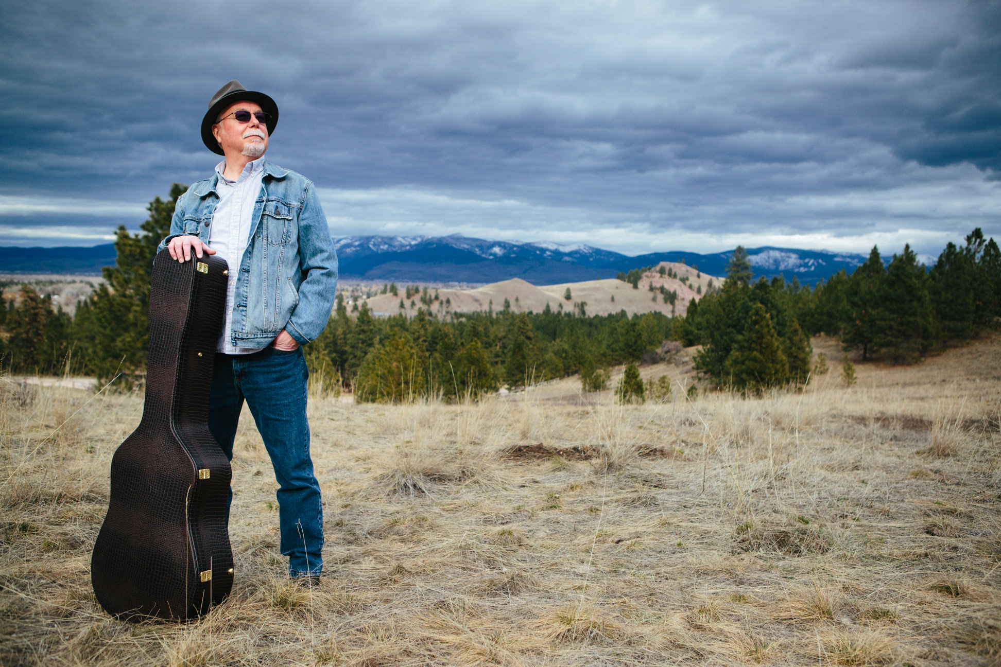 A man poses and leans against his guitar case in Missoula Montana