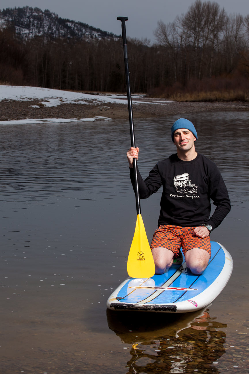 A stand up paddle boarder poses on his paddle board for Stand Up Paddle Board Magazine