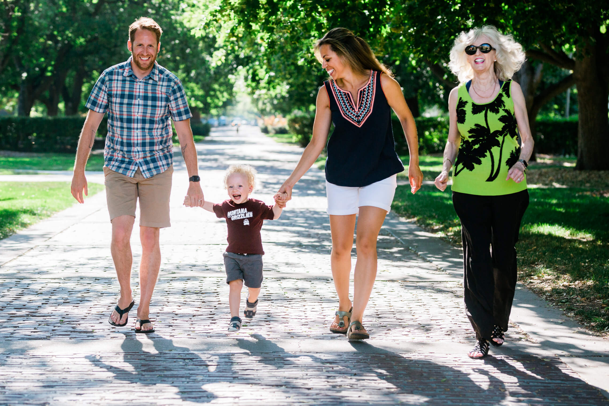 A mother, father, grandmother and toddler laugh and smile during their family session in Missoula Montana at the University of Montana