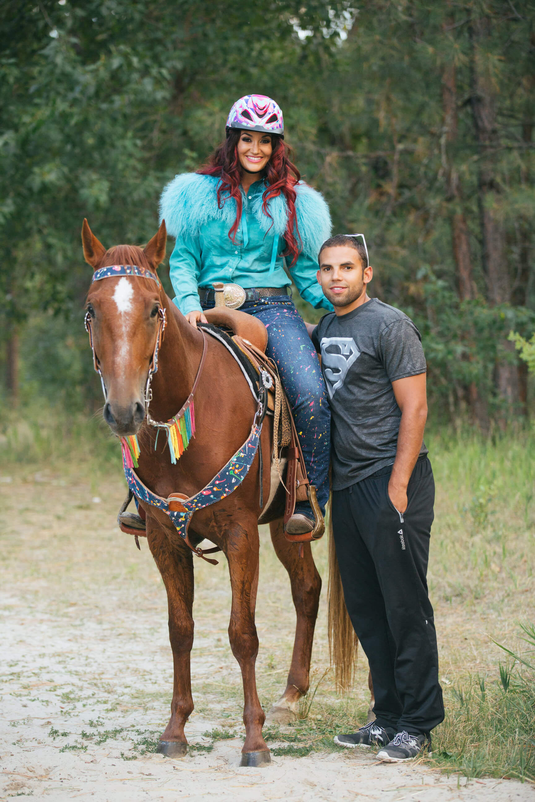Fallon Taylor sits atop her horse Babyflo while her husband stands alongside them